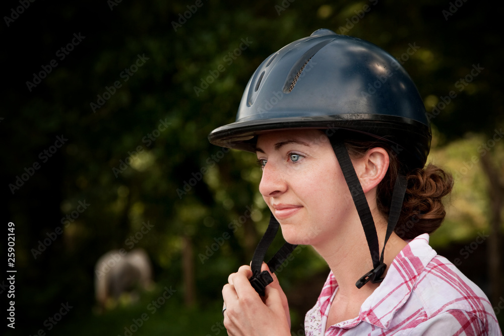 Costa Rican tourist putting on equestrian helmet Costa Rican tourist putting on equestrian helmet