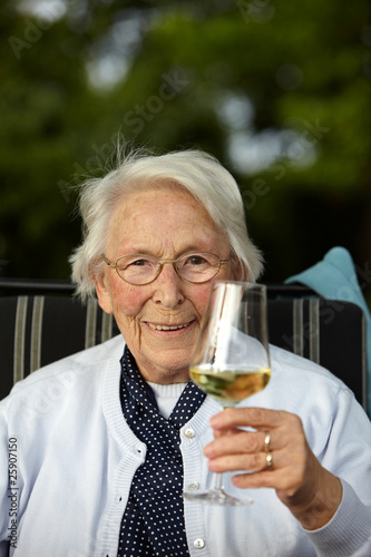 Nette alte Dame mit Wein lächelnd