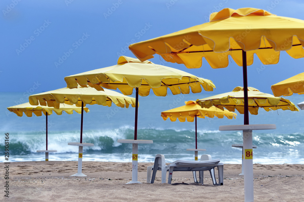 Yellow sun protecting umbrellas on a deserted beach