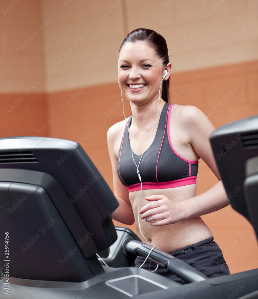 Radiant athletic woman with earphones exercising on a running ma Radiant athletic woman with earphones exercising on a running ma