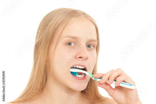 A young woman looks to the camera while brushing her teeth