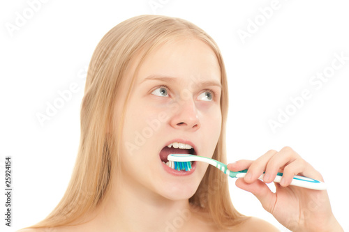 A young woman looks to the side while brushing her teeth