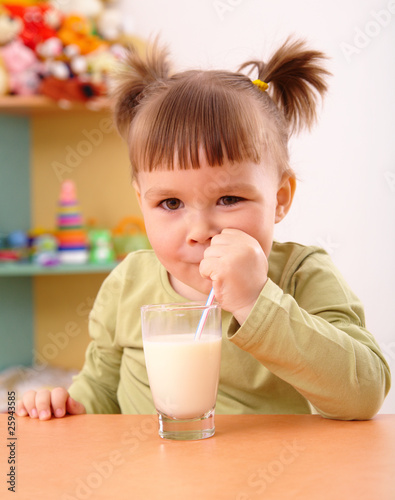 Happy little girl drinks milk