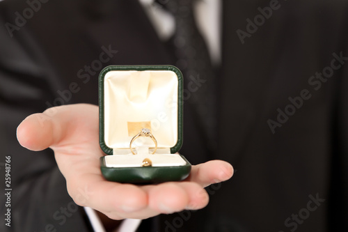 Man in suit holding engagement ring on white isolated background photo