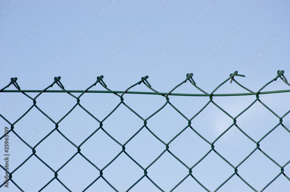 New wire mesh security fence closeup over blue sky New wire mesh security fence closeup over blue sky