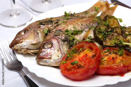 Two Grilled fish with vegetables and herbs on the dish