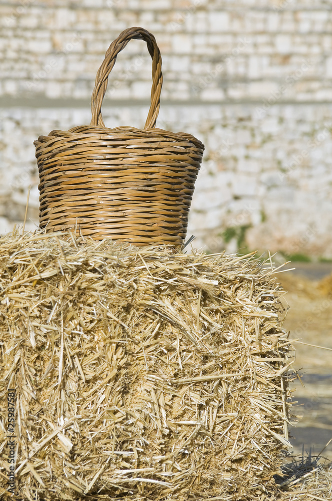 Wicker basket leaning on haystack bale.