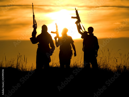 Silhouettes of men with rifles during sunset