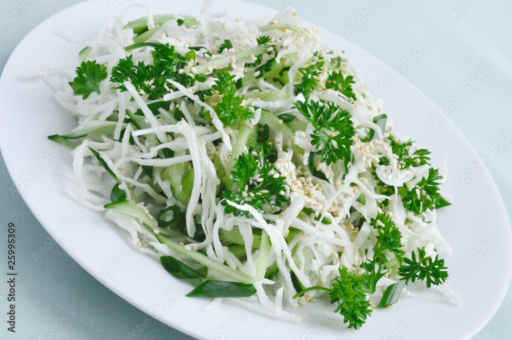 Fototapeta premium Salad of fresh cabbage and cucumber with herbs and sesame