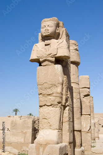 ancient Pharaoh statue and column on backlighted sky background