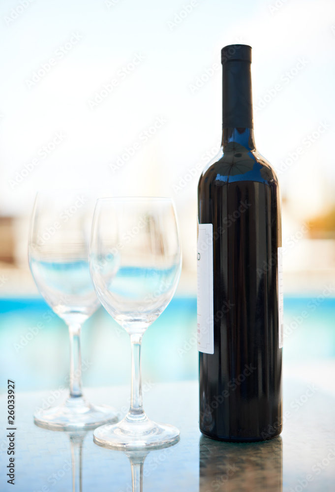 Red wine and glasses near blue water Red wine and glasses near blue water