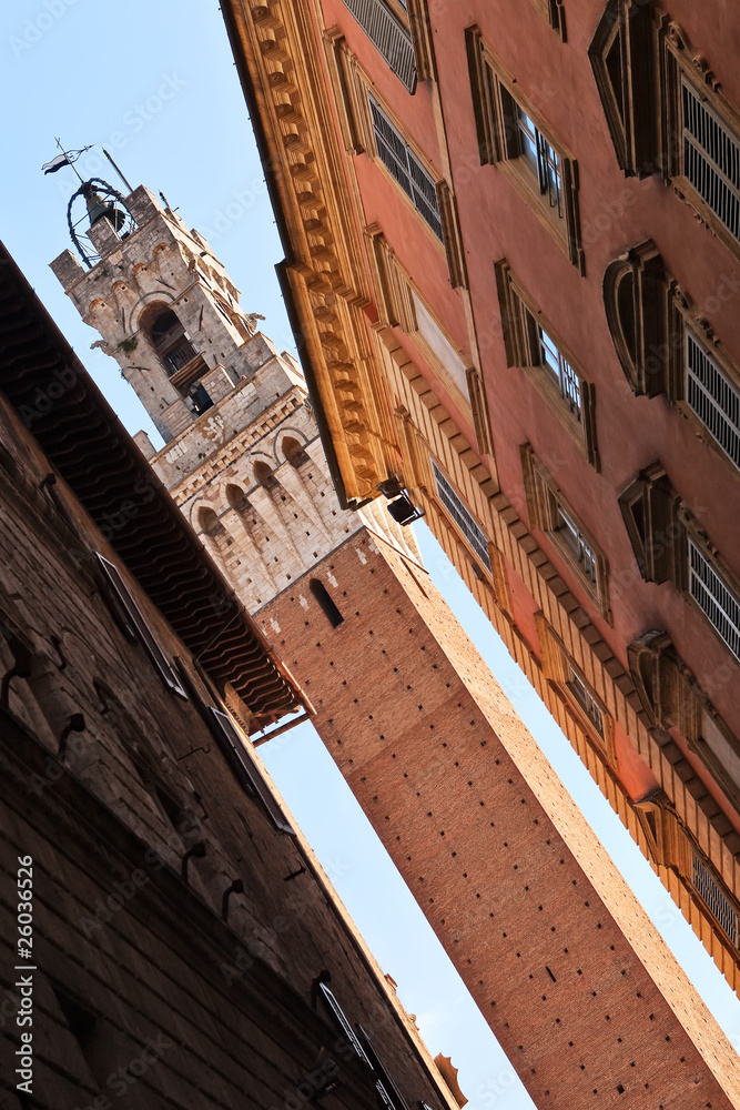 Siena city hall bell tower visibe from narrow street.