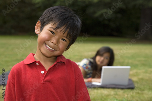 Asian boy smiling with mother in background