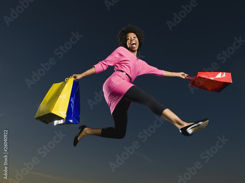 African woman holding shopping bags in mid-air