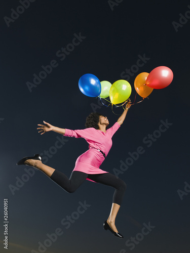 African woman holding bunch of balloons in mid-air