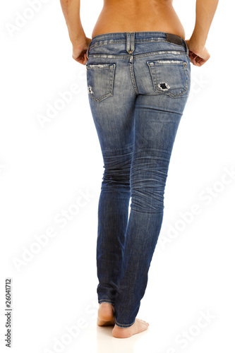 Back side of young woman with bare top wearing worn jeans