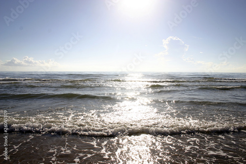 Sun sparkling on the waves as they roll onto the beach