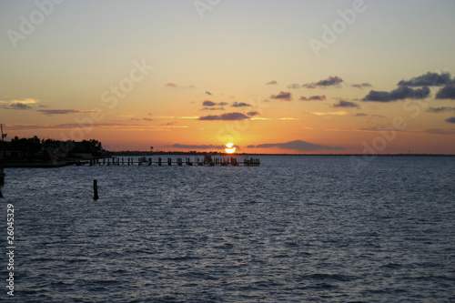 Golden glow of sunset on an ocean bay behind pier