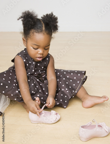 African American girl trying to put shoes on photo