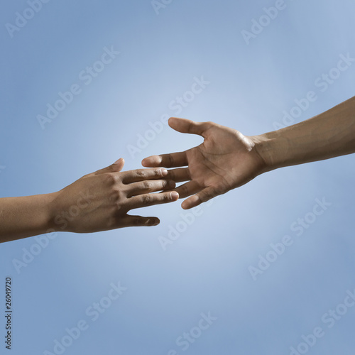 Mixed race people reaching out hands toward one another
