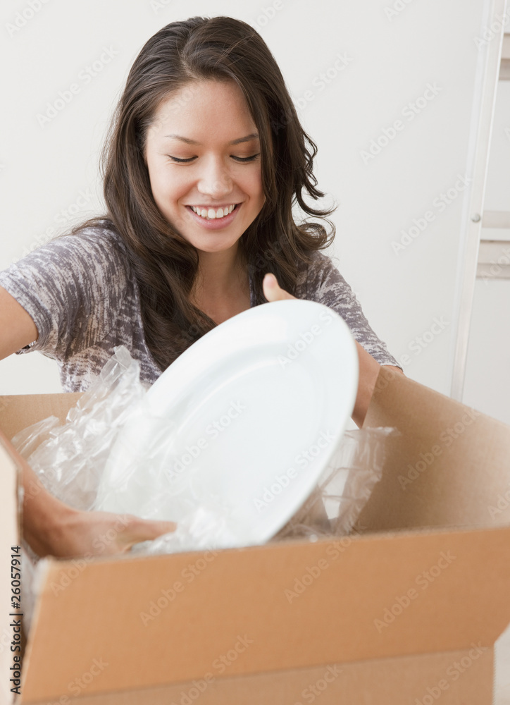 Mixed race woman unpacking dishes Mixed race woman unpacking dishes
