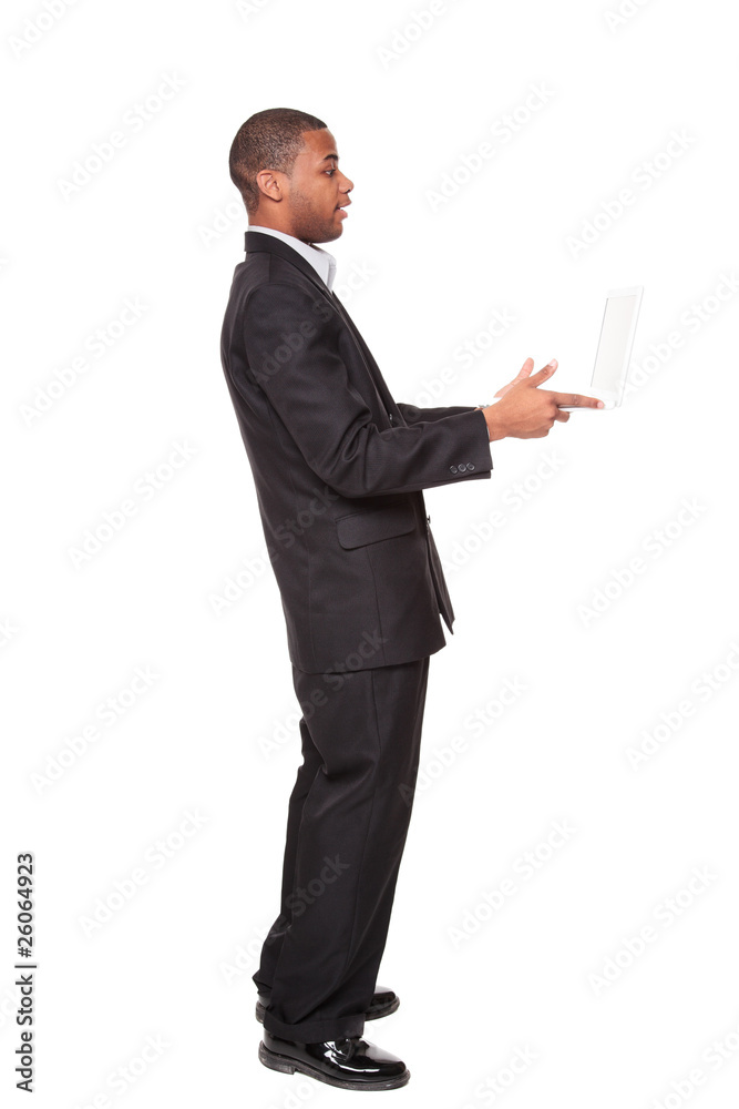 African American businessman looking warily at laptop computer African American businessman looking warily at laptop computer