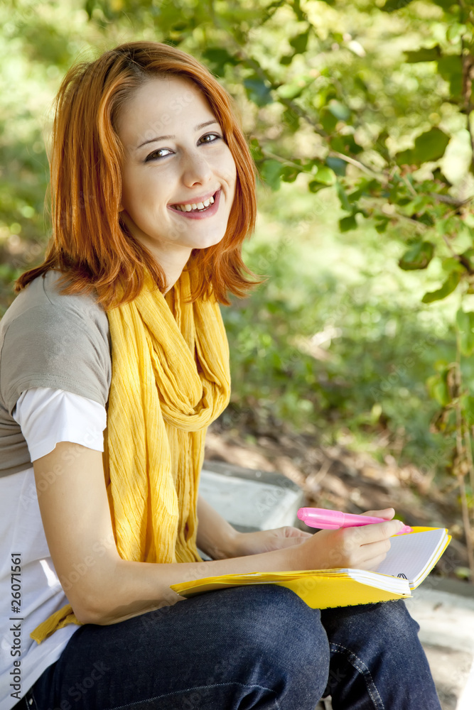 Obraz premium Red-haired student girl with notebook sitting at outdoor.