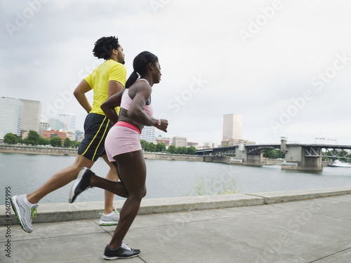 Couple running along urban waterfront photo