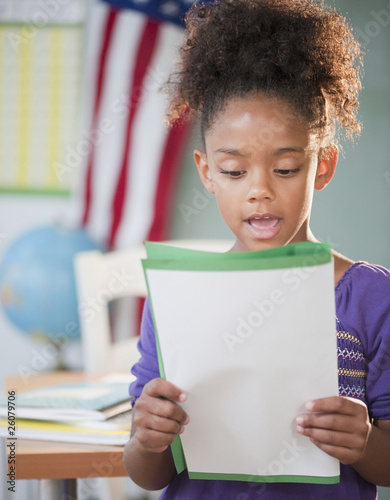 Mixed race girl reading report at school