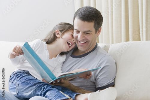 Hispanic father reading book to daughter photo