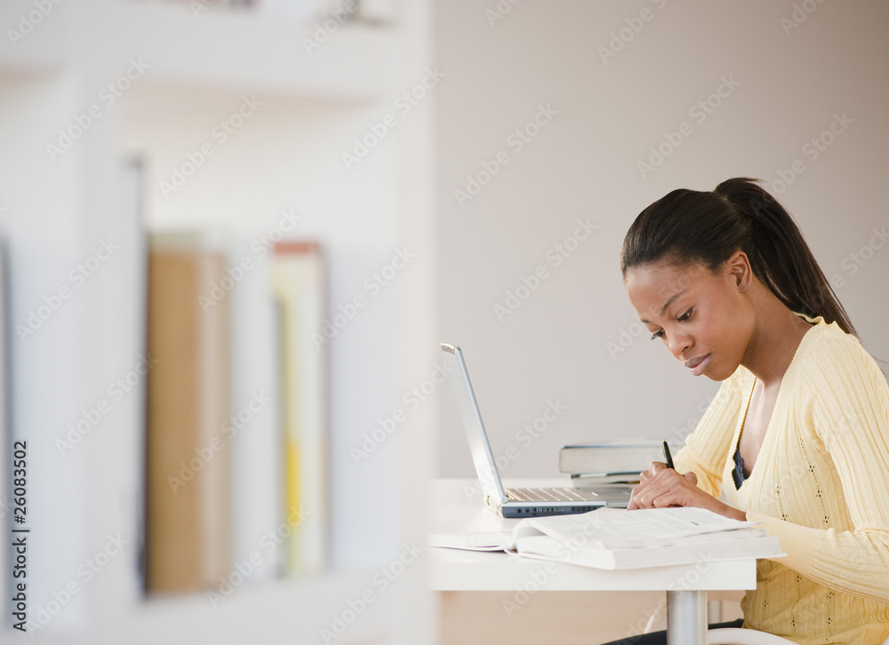 Mixed race woman doing homework with laptop Mixed race woman doing homework with laptop