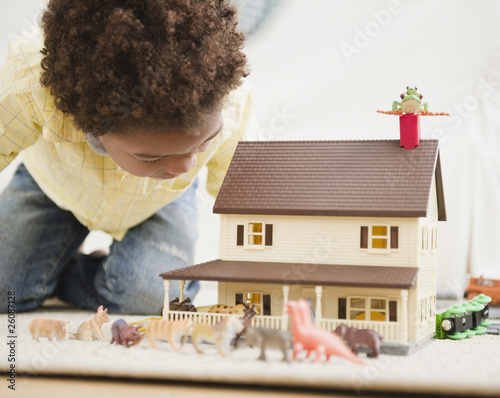 Black boy playing with toy house and animals