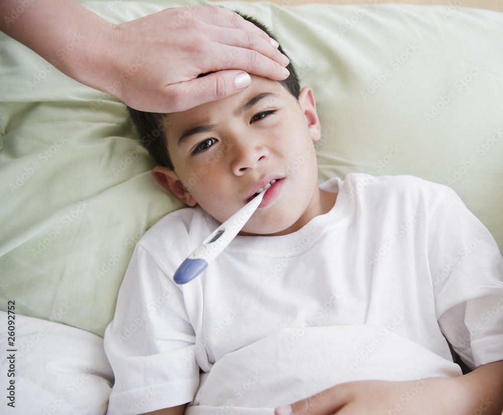 Sick mixed race boy having is temperature taken Sick mixed race boy having is temperature taken