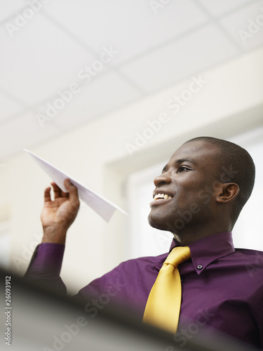 Black businessman throwing paper airplane