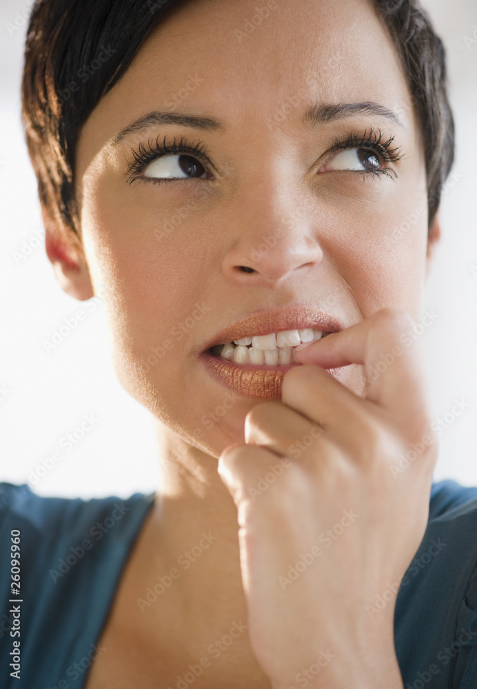 Mixed race woman with short hair biting fingernail Mixed race woman with short hair biting fingernail