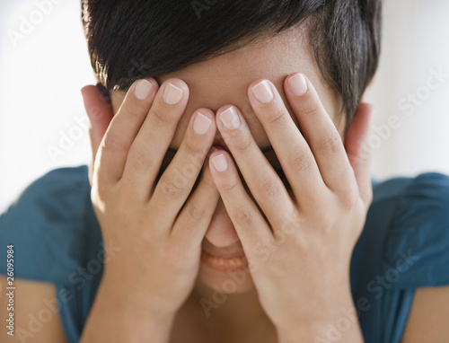 Mixed race woman covering face with hands
