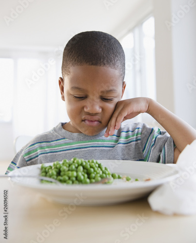 African American grimacing at plate of peas photo