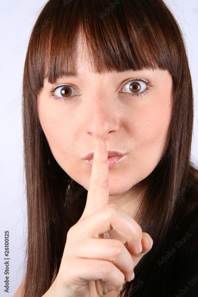 Young woman holding an index finger to her lips- Young woman holding an index finger to her lips-