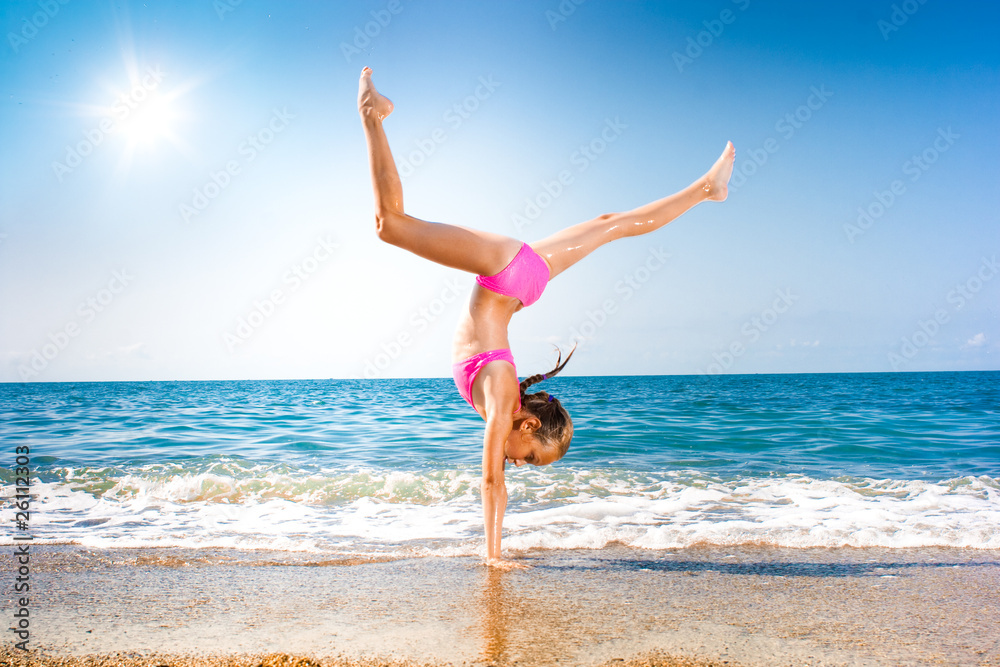 schoolgirl making gymnastics on seashore