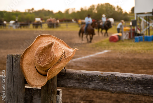 Cowboy hat hung on the fence at a rodeo with horses and riders