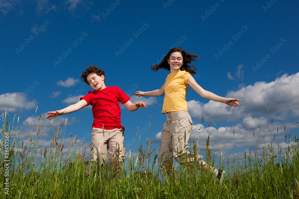 Girl and boy jumping, running against blue sky Girl and boy jumping, running against blue sky