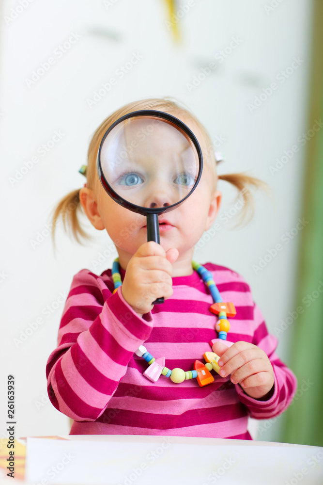Toddler girl playing with magnifier Toddler girl playing with magnifier