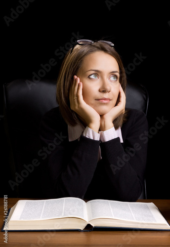 young woman with book at the desk on black background