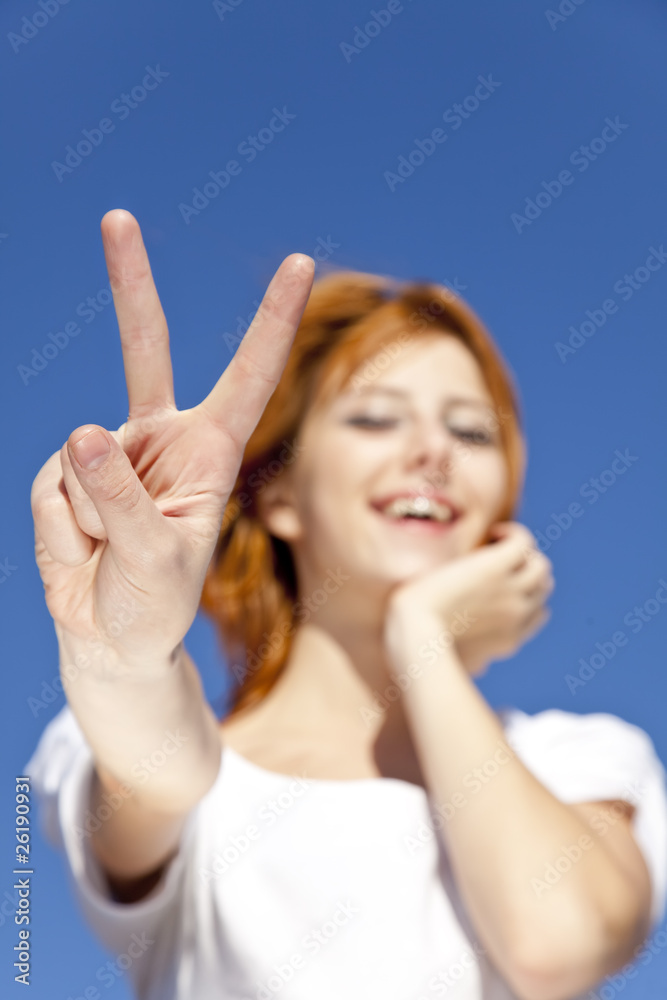 Portrait of red-haired girl in white which show hand V symbol. Portrait of red-haired girl in white which show hand V symbol.