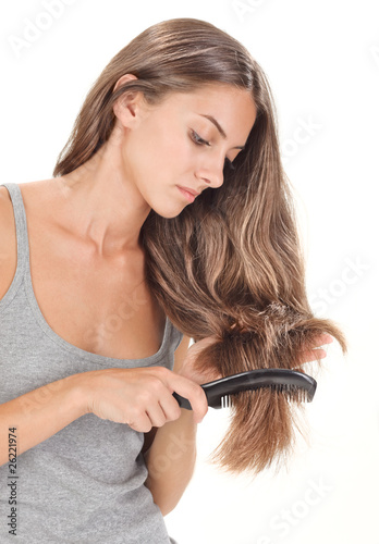 Young brunette beautiful lady combing long hairs on white