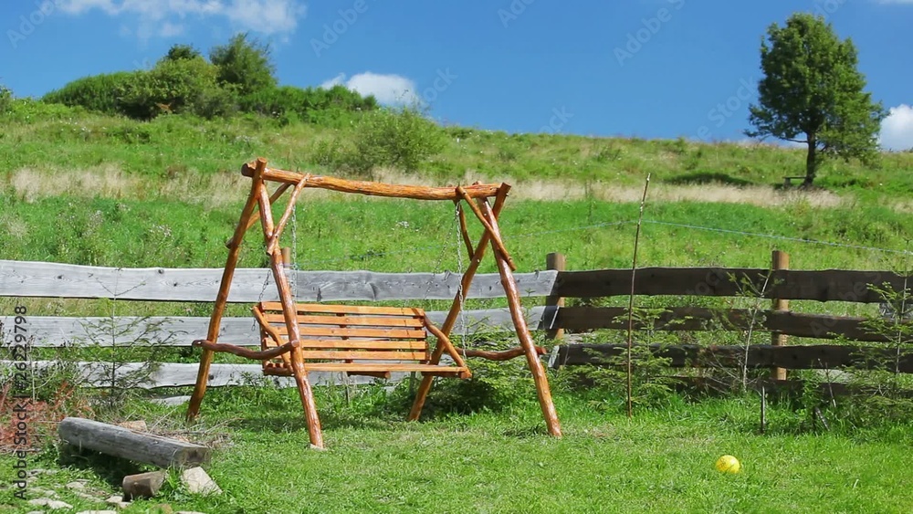 Empty chain swing swaying in rural playground Empty chain swing swaying in rural playground