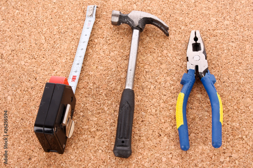 Hammer, pliers and ruller on cork board surface Hammer, pliers and ruller on cork board surface