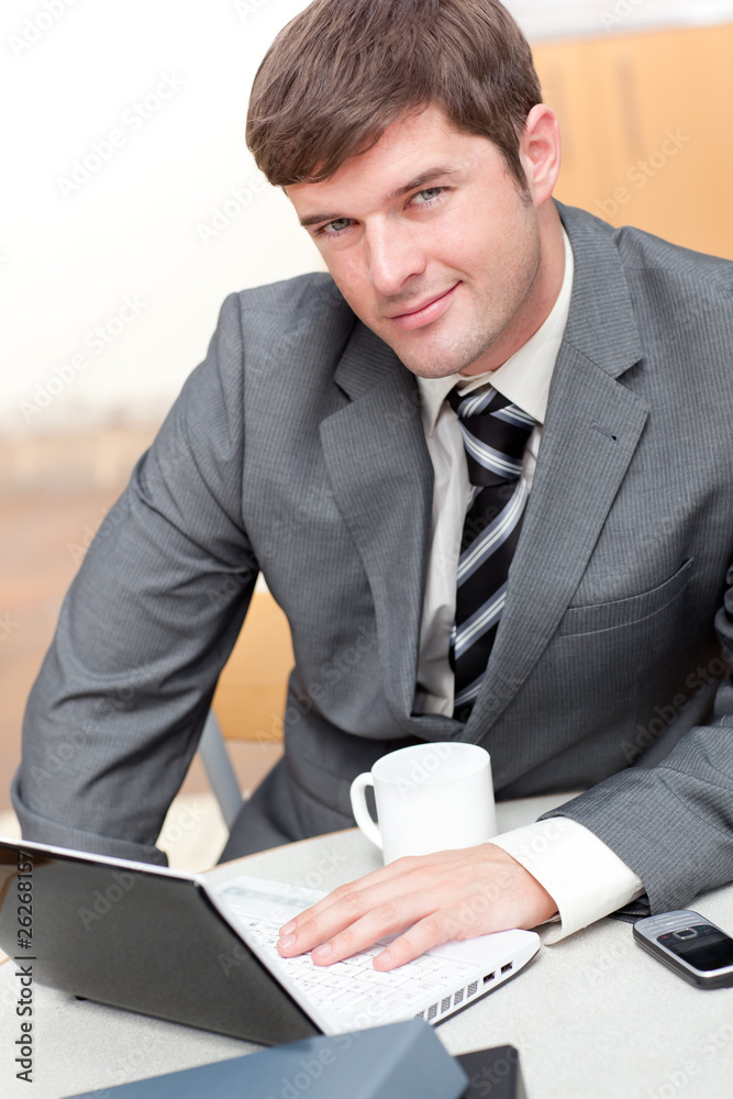 Busy businessman with a laptop, a cellphone and a mug sitting at Busy businessman with a laptop, a cellphone and a mug sitting at