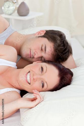 Smiling caucasian couple lying on bed