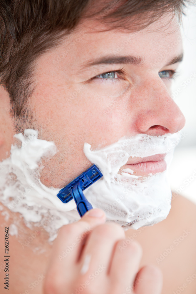 Bright caucasian man shaving in the bathroom